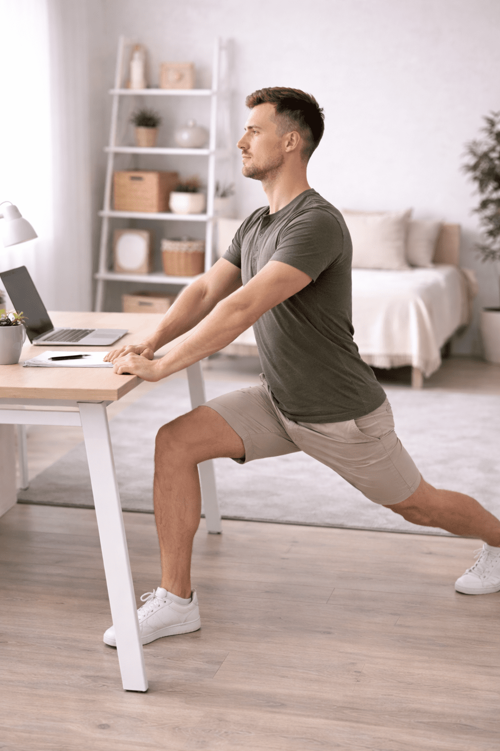 Mann utfører stående hofteleddsbøyer-stretch ved kontorpult — tøyning av iliopsoas